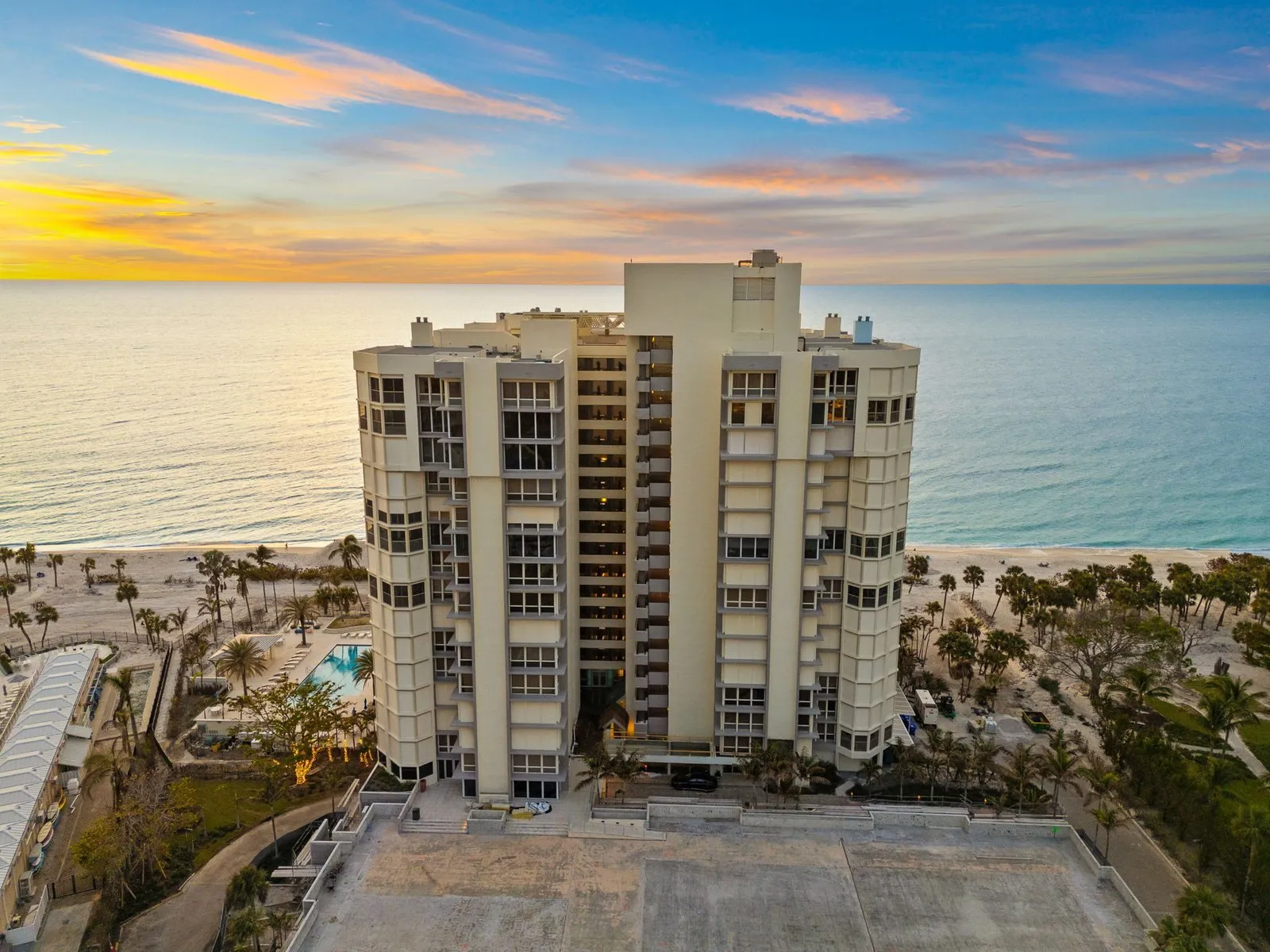 Drone photo of a beachfront condo tower at sunset on the Gulf of Mexico