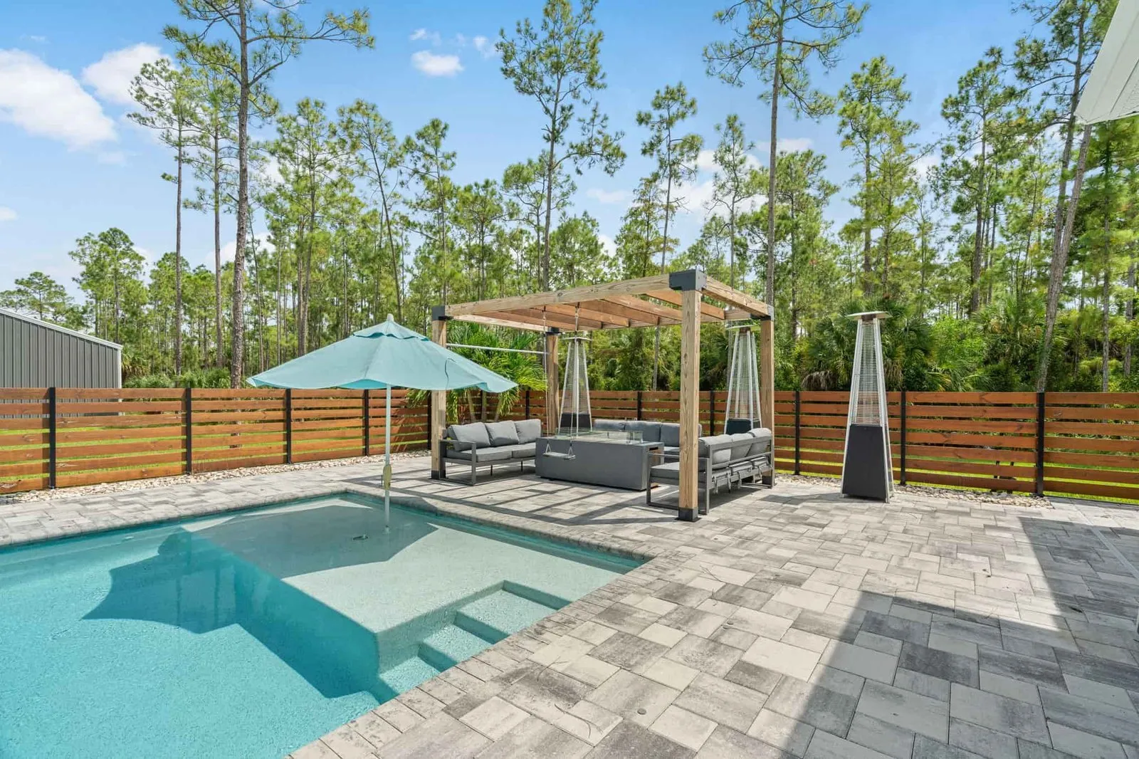 Backyard pool with a paver deck, pergola and privacy fence
