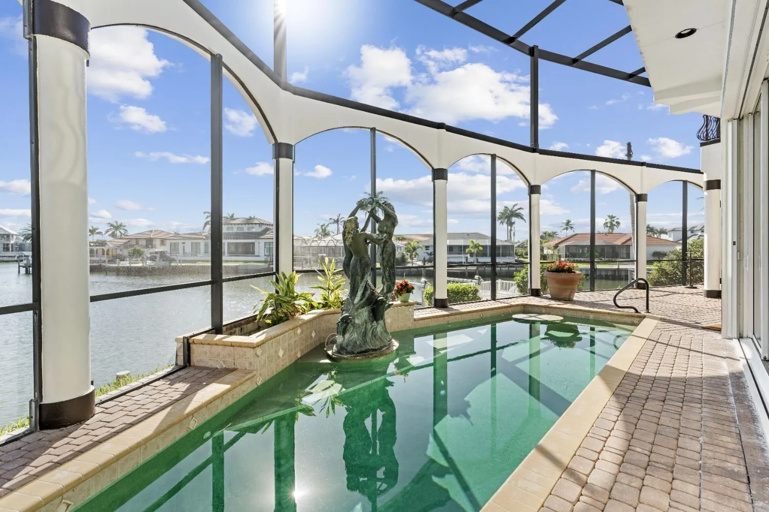 Pool lanai with arched screen framing and a spa