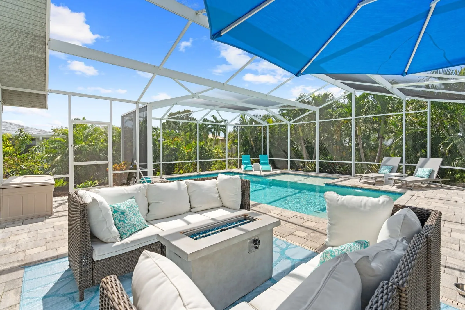 Screened pool lanai with lounge seating and a blue umbrella