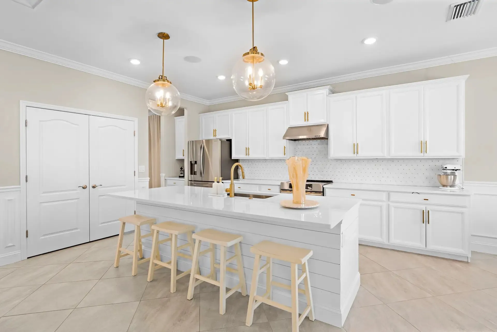 White kitchen with glass pendants and a large island